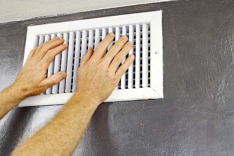 two hands in front of white wall vent