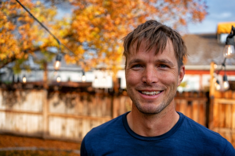 Young Blue-Collar Man Portrait In a Back Yard During The Fall Smiling at the Camera.