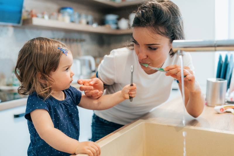 Why Get a Water Filtration System? - Mother and daughter baby girl brushing their teeth together.